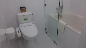 a white bathroom with a toilet and a bath tub at Saigon Sky Garden Serviced Apartments in Ho Chi Minh City