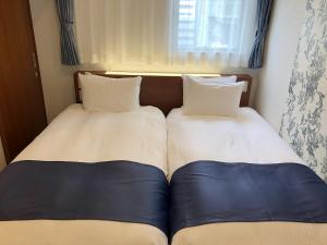 two beds sitting next to each other in a bedroom at S.Training Center Hotel Osaka in Osaka