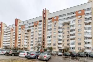 Helen Apartments Galleria Minsk في مينسك: عمارة سكنية كبيرة فيها سيارات تقف في موقف للسيارات