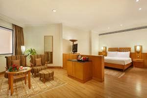 a hotel room with a bed and a table and chairs at Trident Chennai in Chennai
