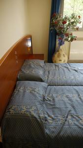 Una cama con un edredón azul y un jarrón con una planta en Albergo Ristorante Sterlina, en Grizzana