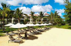 een rij stoelen en parasols op een strand bij Tarisa Resort & Spa in Mont Choisy