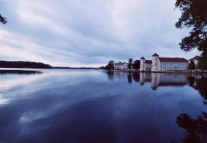 vista su un grande lago con case ed edifici di Marstall im Schlosspark Rheinsberg a Rheinsberg