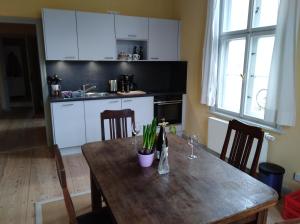 una cocina con mesa de madera con sillas y una cocina con armarios blancos. en Marstall im Schlosspark Rheinsberg, en Rheinsberg