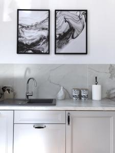 three framed pictures on a wall above a kitchen sink at Piper Park Wilsona & Targi in Poznań
