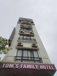 a tall white building with a family hotel sign on it at Tom's Family Hotel in Ha Long