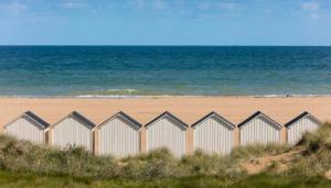 a row of beach huts on a sandy beach at Le Riva Plage Appartement in Ouistreham