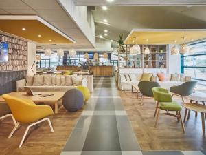 a lobby with couches and tables and chairs at Campanile Poitiers - Site du Futuroscope in Chasseneuil-du-Poitou