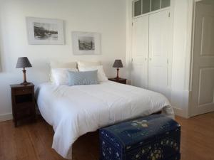 a bedroom with a white bed with a blue ottoman at CASA AURORA S. MARCOS in Figueira da Foz