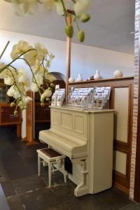 a white piano in a room with flowers at Fletcher Hotel De Zalm in Brielle