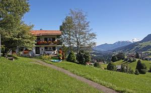 una casa in cima a una verde collina con una strada di Ferienhaus Windegge a Hirschegg