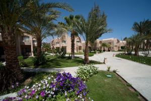 a garden with palm trees and flowers in front of a house at Shams Alam Beach Resort in Abū Ghuşūn