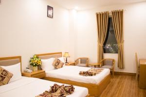 una camera d'albergo con due letti e una finestra di Hoài Thương Hotel a Pleiku