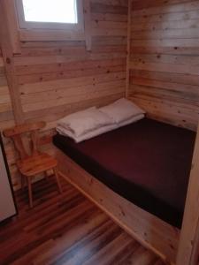 a room with a bed and a chair in a cabin at Maly Domek Zalesie in Barczewo