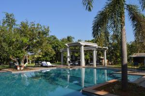 a swimming pool with a gazebo and a palm tree at Heritage Resort Hampi in Hampi