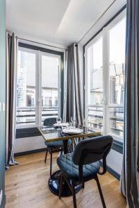 a dining room with a table and chairs and windows at CMG Champs Elysées - Boetie 4DD in Paris