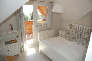 biała sypialnia z łóżkiem i oknem w obiekcie Karkonoski Widok w mieście Dziwiszów
