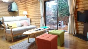 ein Wohnzimmer mit einem Sofa und einem Tisch in der Unterkunft るり渓 フォレストヴィラ in Nantan city