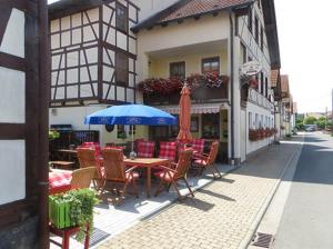 a table and chairs with a blue umbrella on a street at Gasthaus Beyersdorfer in Rieth