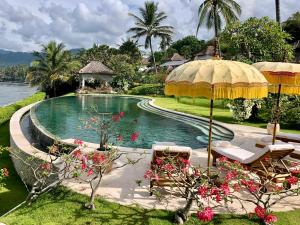 una piscina con sombrilla y algunas flores en Luxury Villa Perla en Candidasa