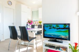 uma sala de estar com televisão e uma mesa com cadeiras em Apartment MaLa em Dubrovnik