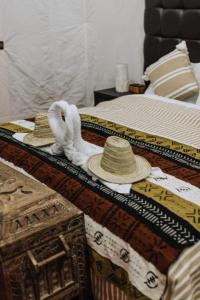 2 camas con toallas y sombreros encima en Desert Luxury Camp Erg Chigaga, en El Gouera