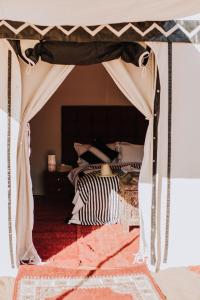 Desert Luxury Camp Erg Chigaga في El Gouera: سرير مع مظلة في الغرفة