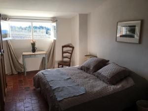 um quarto com uma cama, uma mesa e uma janela em 40 Rue du Ventoux em Bédoin