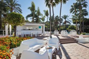 a patio with white chairs and a bar with palm trees at Melia Marbella Banús in Marbella