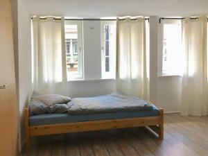 a bed in a room with two windows at Drei-Flüsse Ferienwohnung in Hannoversch Münden