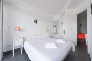 ein weißes Schlafzimmer mit einem weißen Bett und einem roten Stuhl in der Unterkunft Vista Dorada al mar balcón-Wifi By CanariasGetaway in Las Palmas de Gran Canaria