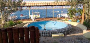 a swimming pool next to the water with a boat at Divers home in Ras al Khaimah