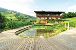 a house with a pond in front of a building at Ski in Ski out Hotel Unterellmau in Saalbach-Hinterglemm