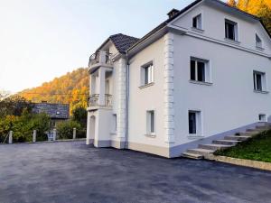 un grand bâtiment blanc avec une colline en arrière-plan dans l'établissement Villa Hillside Apartment, à Jesenice