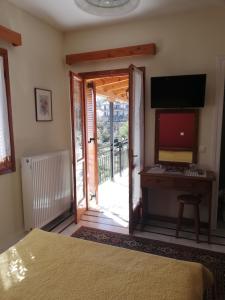 a bedroom with a door open to a balcony with a desk at Dafni Apartments in Kastri