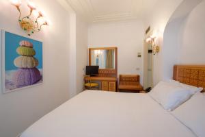 a bedroom with a bed, a desk and a painting on the wall at Grand Hotel Flora in Sorrento