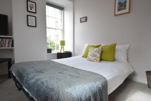 a white bed with green pillows in a bedroom at The Bolthole - Fantastic Old Town Location! in Edinburgh