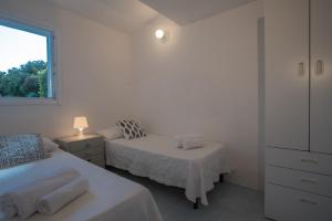 een witte slaapkamer met 2 bedden en een raam bij Sul Mare Sardegna Villa Eudora in Villasimius
