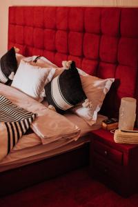 a bed with a red headboard and pillows on it at Desert Luxury Camp Erg Chigaga in El Gouera