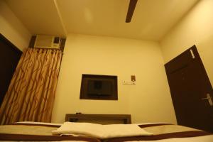 a bedroom with a bed and a tv and a window at Nestlay Rooms Ambattur in Chennai