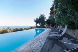 a swimming pool with chairs and the ocean in the background at Villa Corinna in Ventimiglia
