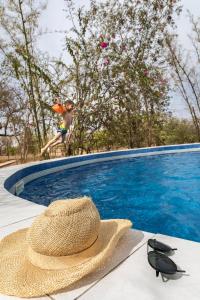 ein Strohhut auf einem Tisch neben einem Pool in der Unterkunft Sougri Doogo in Loumbila