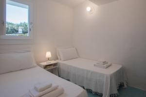 een witte kamer met 2 bedden en een raam bij Sul Mare Sardegna Villa Eunice in Villasimius