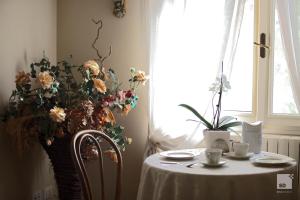 a table with a white table cloth and a vase of flowers at Locanda Dei Cinque Cerri in Sasso Marconi