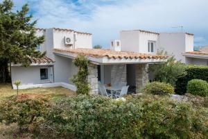 een wit huis met een tafel en stoelen in de tuin bij Sul Mare Sardegna Villa Eunice in Villasimius