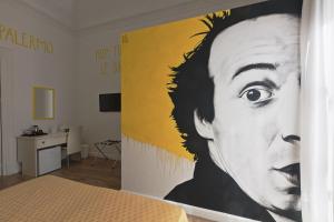 a bedroom with a large painting of a man on the wall at Afea Art & Rooms in Palermo