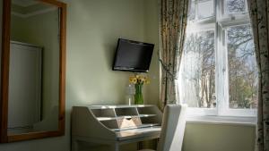 a room with a table and a tv on the wall at Sandfield Guest House in Oxford