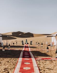 un tapis rouge au milieu d'un désert dans l'établissement Desert Luxury Camp Erg Chigaga, à El Gouera