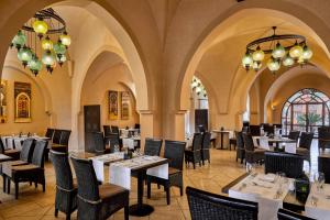 a restaurant with tables and chairs and chandeliers at Jaz Dar El Madina in Coraya Bay