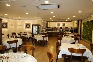 a restaurant with white tables and chairs and a kitchen at Princesa Ana in Granada